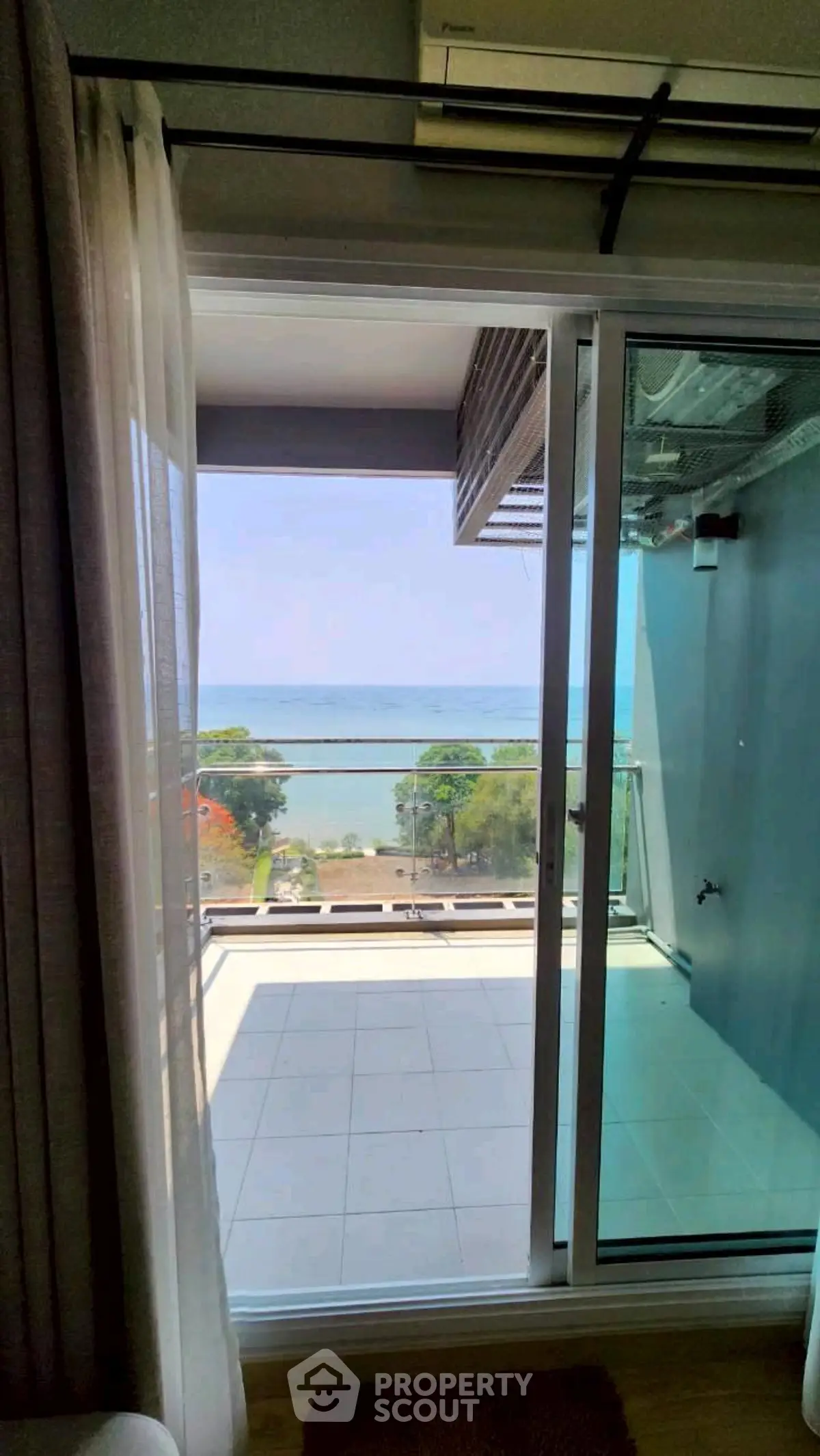 Stunning ocean view from modern apartment balcony with sliding glass doors.