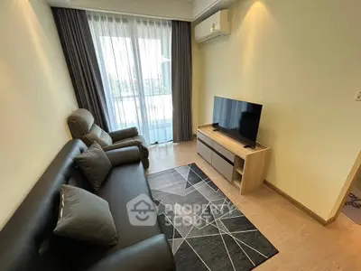 Modern living room with sleek furniture and large window offering natural light.