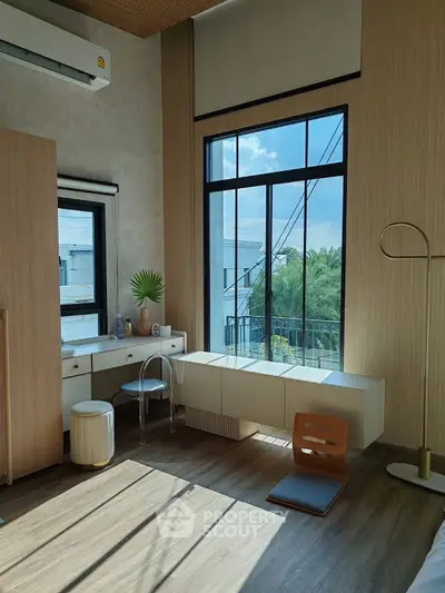 Modern bedroom with large window and stylish decor, offering a serene view.