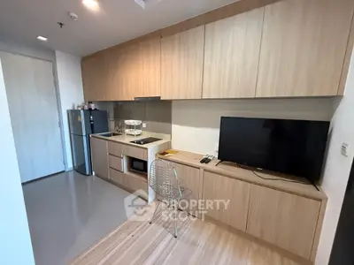 Modern kitchen with sleek wooden cabinets and integrated appliances in a cozy apartment.