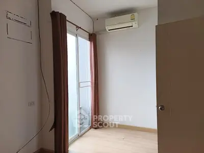 Minimalist bedroom with air conditioning and balcony access, perfect for cozy living.