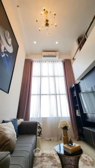 Luxurious high-ceiling living room with elegant chandelier and modern decor.