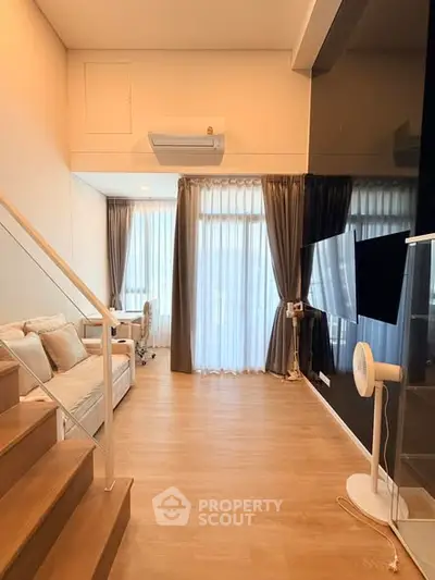 Modern living room with staircase, large windows, and stylish decor