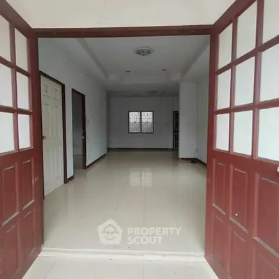 Spacious empty room with tiled flooring and wooden doors, ideal for customization.