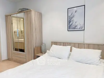 Cozy bedroom with wooden wardrobe and framed artwork, perfect for relaxation.