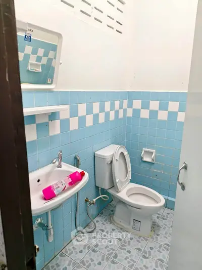 Compact bathroom with blue tiles and essential fixtures, ideal for small spaces.