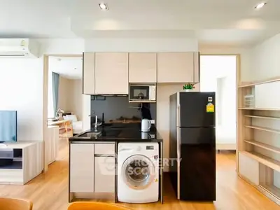 Modern kitchen with integrated appliances and sleek cabinetry in open-plan apartment.