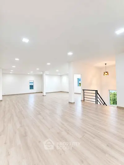Spacious open-plan living area with modern lighting and wooden flooring, ideal for versatile interior design.