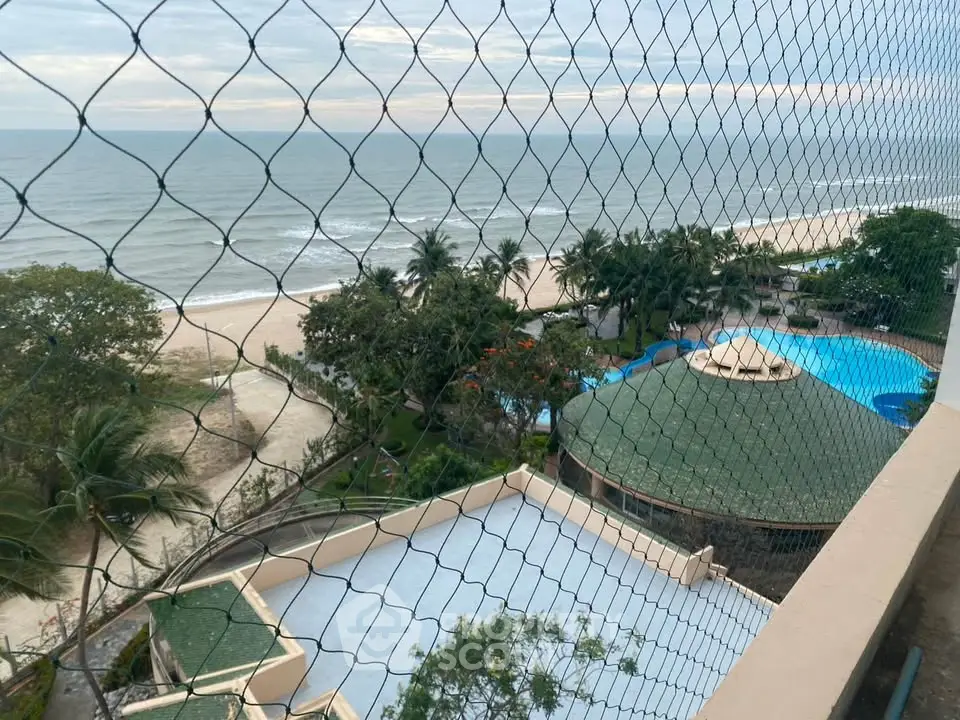 Stunning beachfront view from high-rise balcony overlooking ocean and pool area.