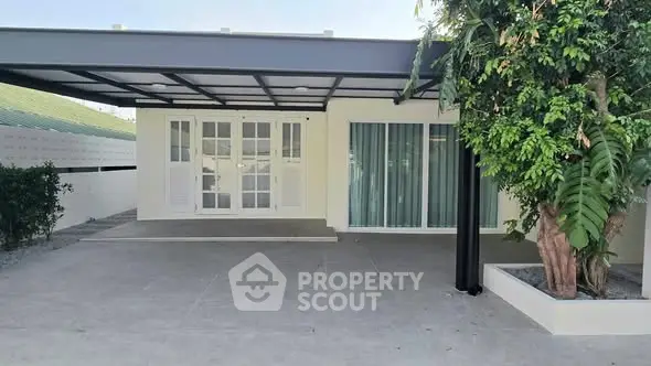 Modern single-story house with covered carport and lush greenery.