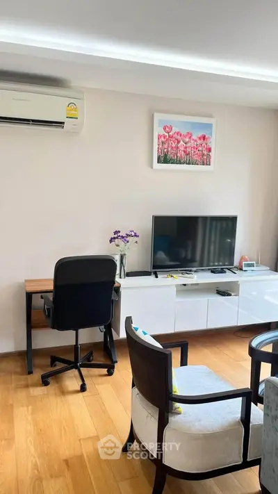 Modern living room with wooden flooring, stylish furniture, and wall-mounted air conditioner.
