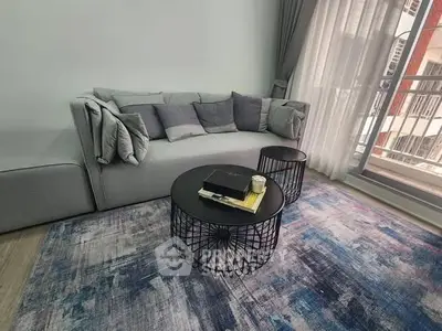 Modern living room with stylish gray sofa and chic round coffee tables on a colorful rug.