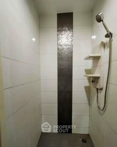 Modern bathroom shower area with sleek tile design and wall-mounted showerhead.