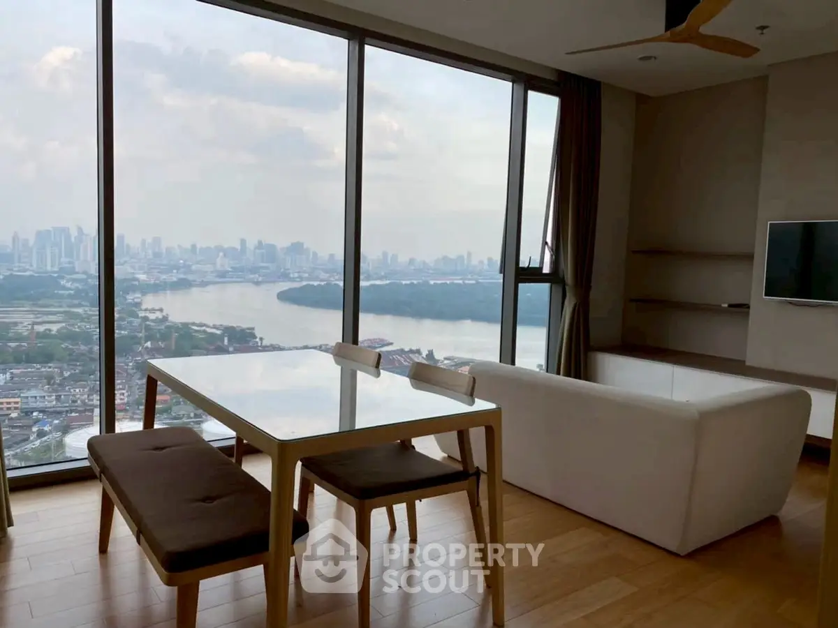 Stunning high-rise living room with panoramic city and river views, modern furniture, and floor-to-ceiling windows.