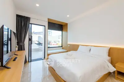 Modern bedroom with sleek design, featuring a large bed, flat-screen TV, and access to a private balcony.