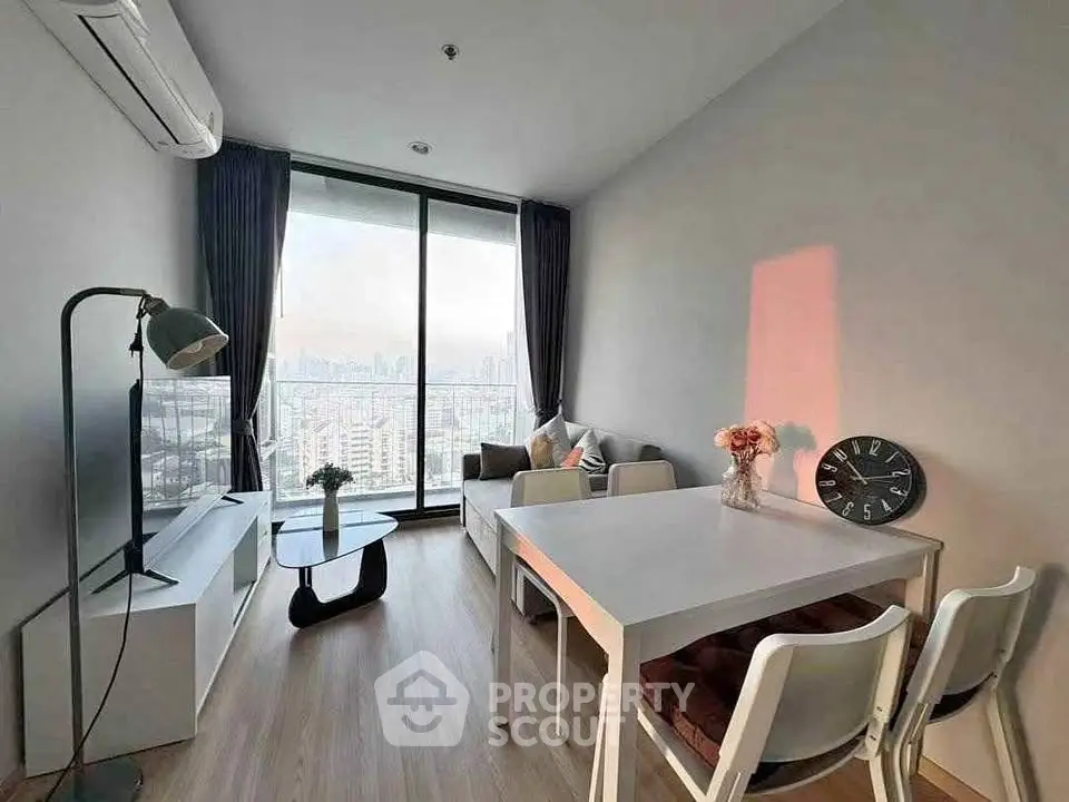 Modern living room with city view, featuring sleek furniture and large windows for natural light.