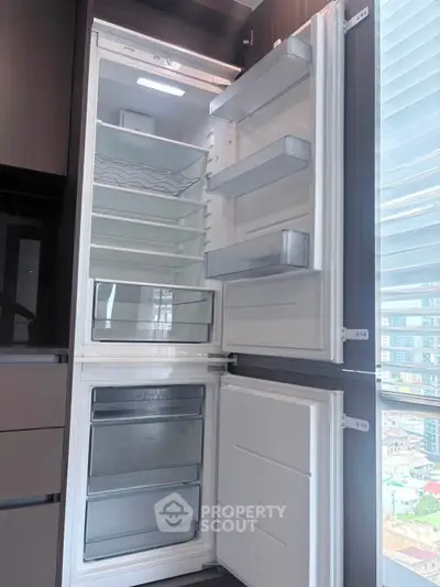Modern built-in kitchen fridge with open doors showcasing spacious interior and sleek design.