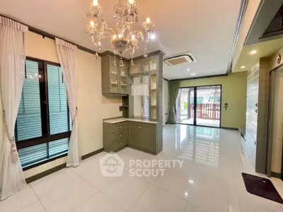 Spacious living room with elegant chandelier and large windows in modern home.