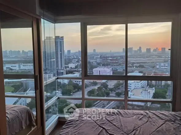 Stunning bedroom with panoramic city view at sunset, featuring floor-to-ceiling windows.