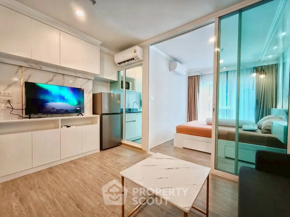 Modern open-plan living room with kitchen and bedroom, featuring sleek design and natural light.
