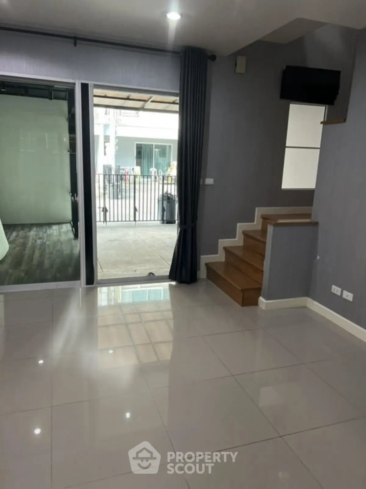 Modern interior with sleek staircase and large glass doors leading to outdoor area.