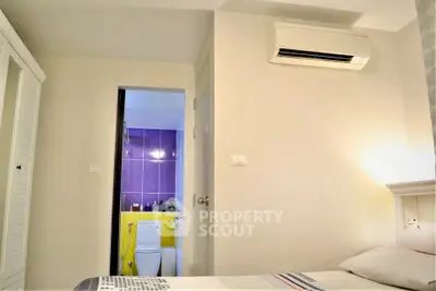 Modern bedroom with air conditioning and view into a vibrant bathroom