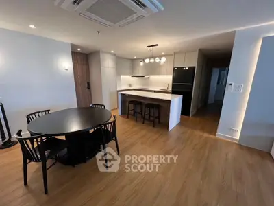 Modern open-plan kitchen and dining area with sleek design and wooden flooring.