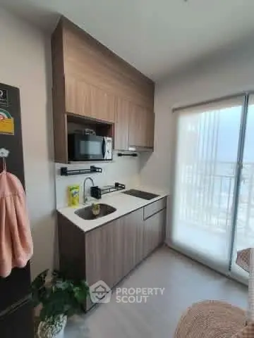 Modern compact kitchen with wooden cabinets and balcony view