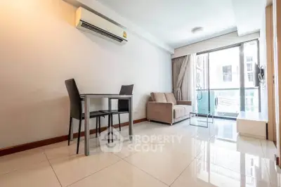 Modern living room with sleek furniture and large windows leading to a balcony.