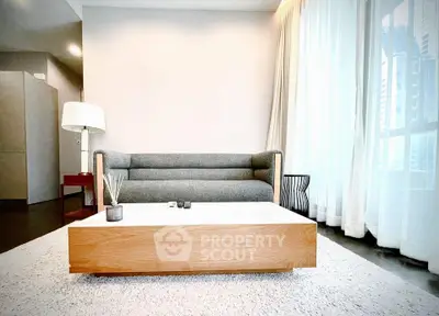 Modern living room with stylish sofa and coffee table, featuring floor-to-ceiling windows for natural light.