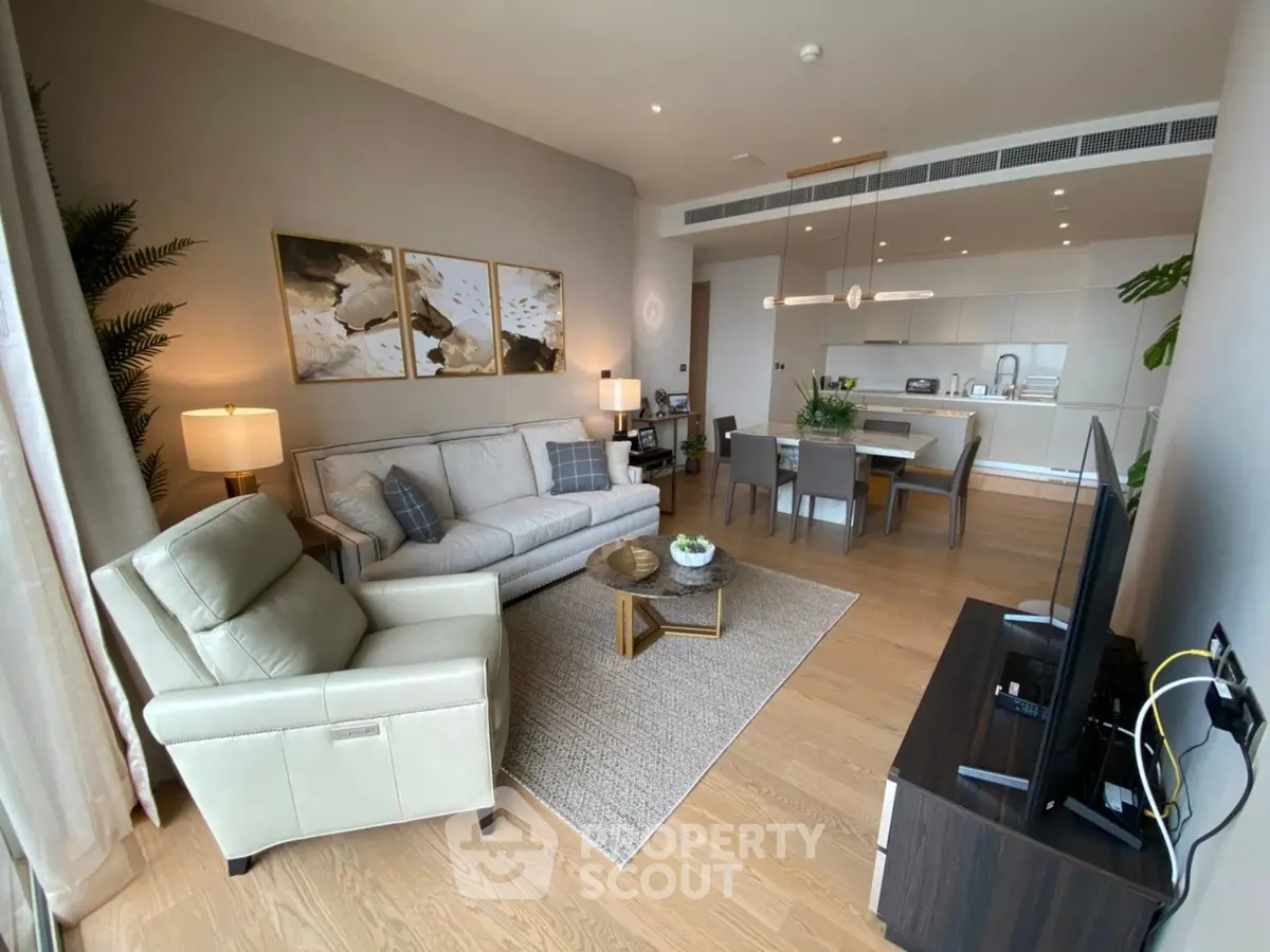 Spacious modern living room with open kitchen, elegant decor, and natural light.