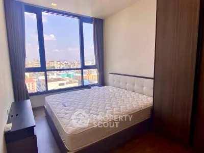 Modern bedroom with large window offering city view, featuring a comfortable bed and sleek wooden furniture.