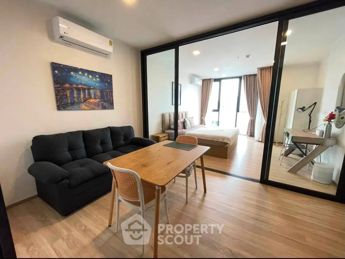 Modern open-plan living room with cozy sofa and dining area leading to a stylish bedroom.