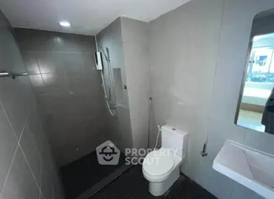 Modern bathroom with sleek gray tiles and contemporary fixtures, featuring a shower and toilet.