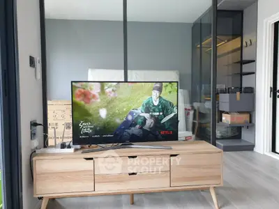 Modern living room with sleek TV stand and glass partition, showcasing contemporary design.