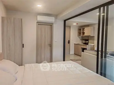 Modern bedroom with sliding glass doors leading to a cozy living area and kitchen.