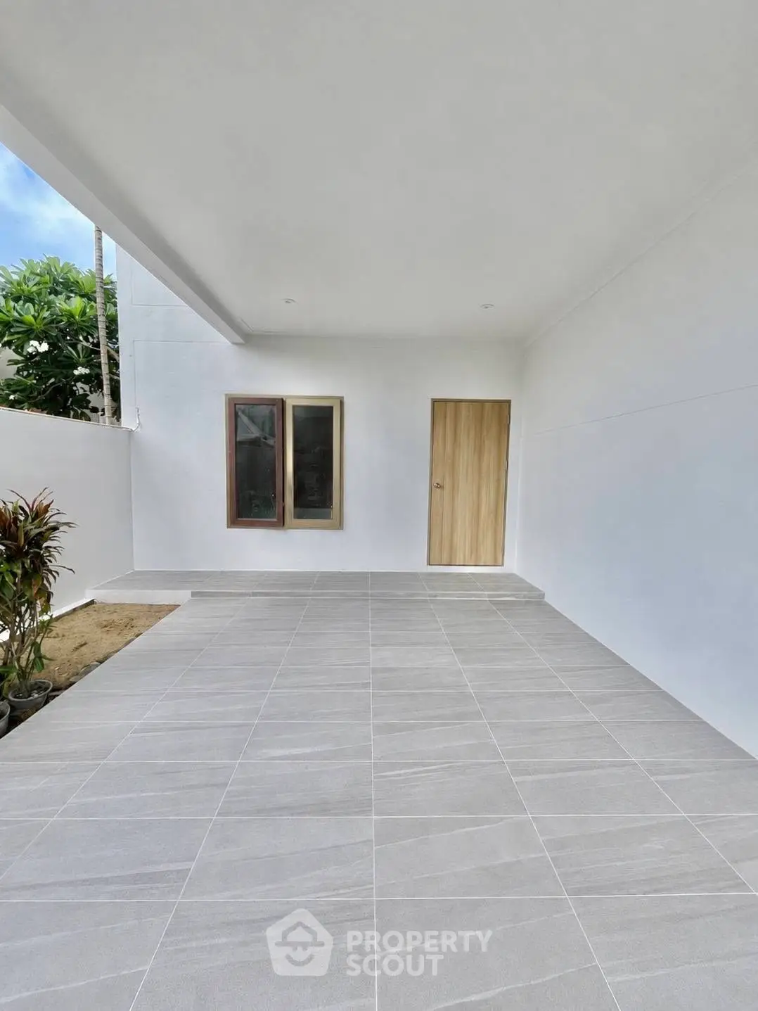 Modern minimalist exterior with sleek tiled flooring and wooden door entryway.