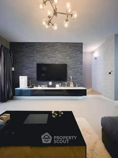 Modern living room with stylish decor and large TV, featuring elegant lighting and sleek furniture.