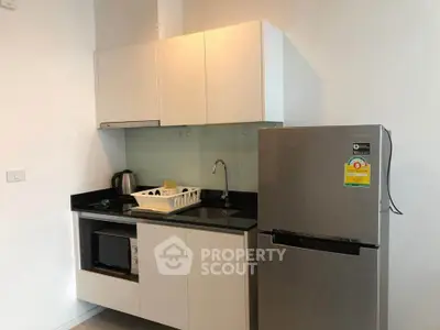 Modern compact kitchen with sleek cabinets and stainless steel fridge