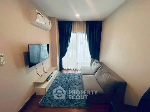 Cozy living room with modern sofa, wall-mounted TV, and large window with curtains.