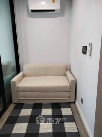 Cozy small living area with modern sofa and air conditioning, perfect for compact spaces.