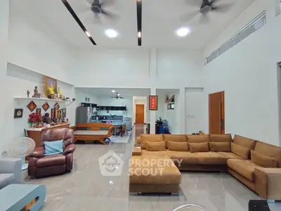 Spacious living room with modern decor and open layout, featuring a large sectional sofa and stylish ceiling fans.