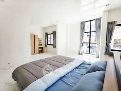 Spacious bedroom with large windows and modern decor in a bright apartment.