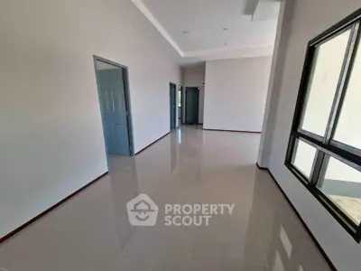 Spacious empty room with glossy tiled floors and large windows in modern home.