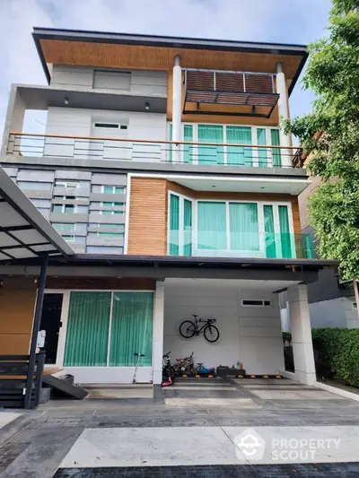 Modern three-story house with large windows and a spacious driveway