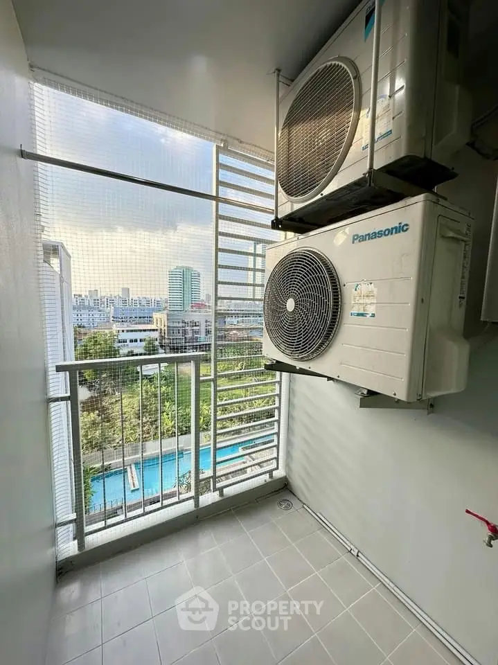 Modern balcony with air conditioning units and city view, overlooking a pool area.