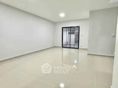 Spacious empty room with glossy tiled floor and large window, perfect for customization.