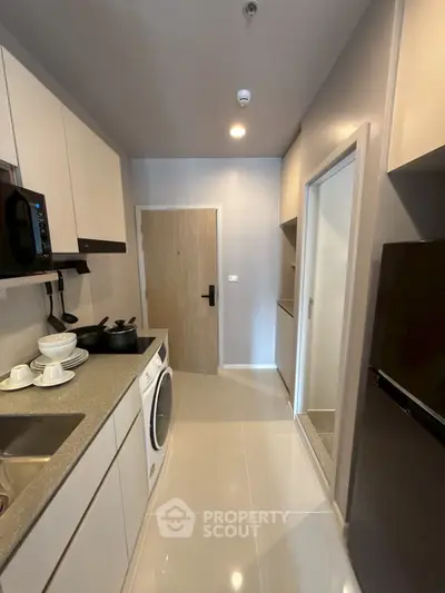 Modern kitchen with sleek cabinetry, washing machine, and appliances in a compact layout.