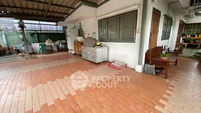 Spacious covered outdoor area with tiled flooring and seating, ideal for gatherings.