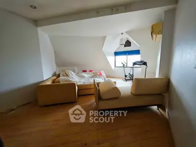 Spacious attic living room with cozy sofa and exercise equipment, perfect for relaxation and fitness.